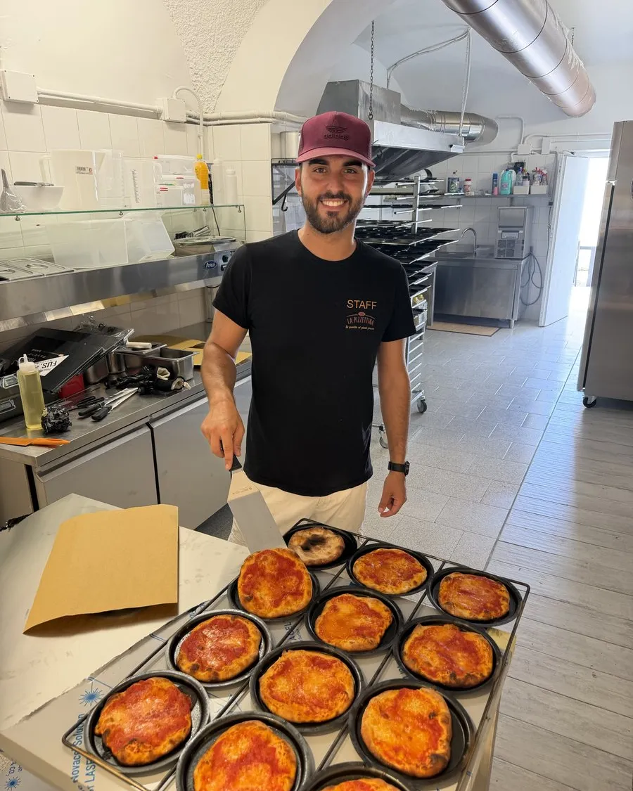 Le mani del nostro pizzaiolo stendono l'impasto nel padellino