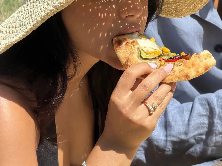 Una cliente assapora la pizzetta al sole